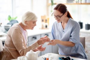 An elderly woman receives medication help from a nurse, showcasing personalized services for long-term mental health in Solon.