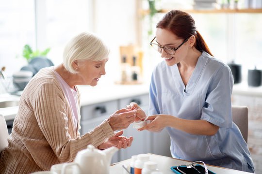 An elderly woman receives medication help from a nurse, showcasing personalized services for long-term mental health in Solon.